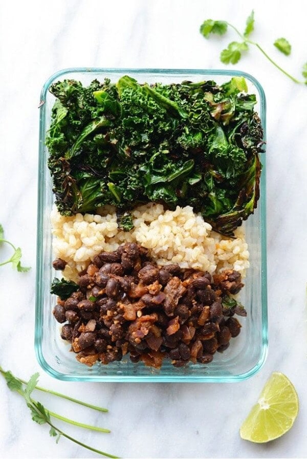Healthy meal prep recipe of kale, black beans and rice in a glass container.