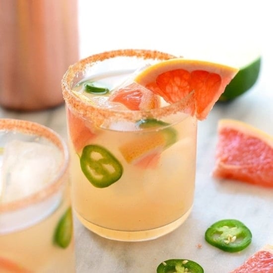 Two glasses of tangy grapefruit margaritas garnished with jalapeños and limes.