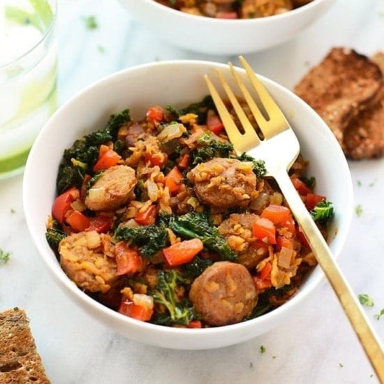 A sweet potato and kale hash with sausage, served with bread and a fork.