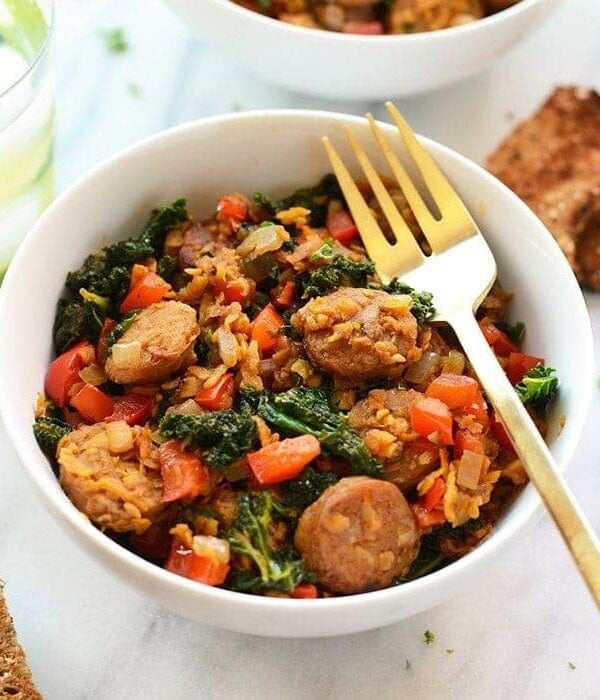 A sweet potato and kale hash with sausage, served with bread and a fork.