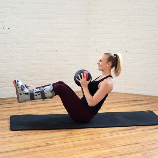 a woman performing an abs-strengthening exercise with a stability ball on a mat.