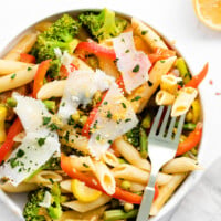 A bowl of pasta primavera with vegetables and Parmesan cheese.