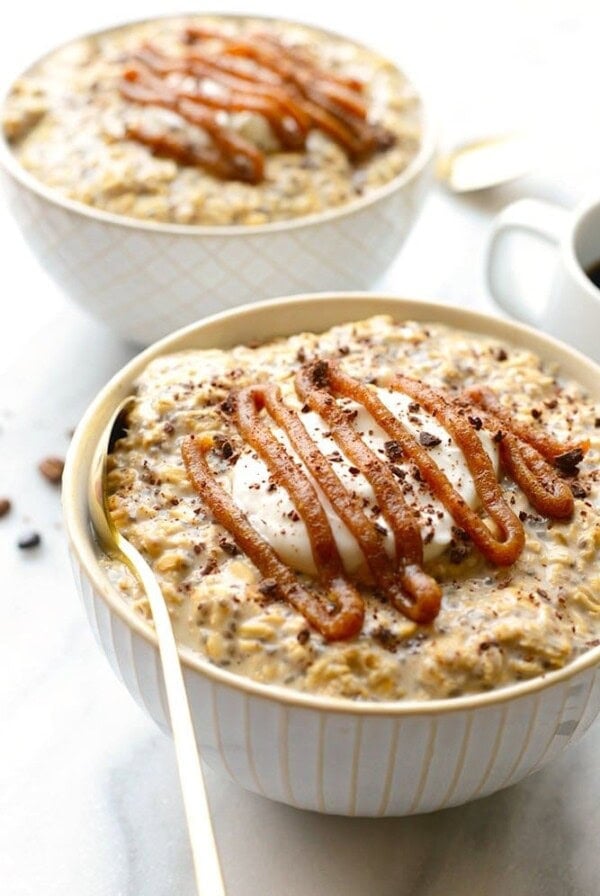 A breakfast consisting of two bowls of Espresso Overnight Oats drizzled with caramel sauce, accompanied by a cup of coffee.