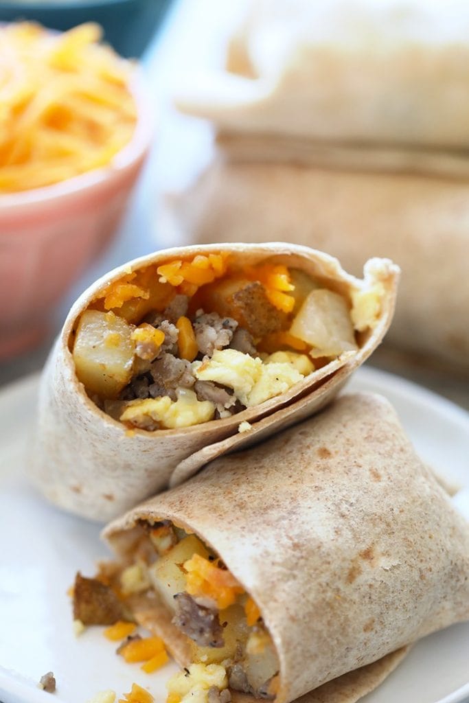 Breakfast burritos on a plate with cheese and eggs.
