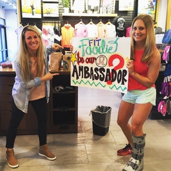 two women standing in front of a store with a sign.