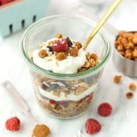 Chickpea granola in a glass with raspberries and chia seeds.