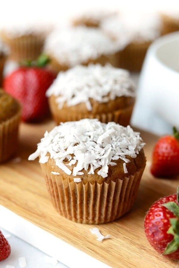 Coconut blender cupcakes with strawberries on a wooden cutting board.