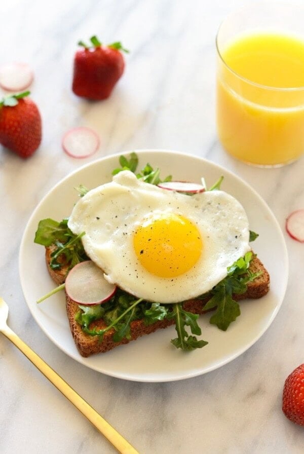 A plate of toast featuring a perfectly cooked fried egg and radishes, perfect for Toast Tuesday.