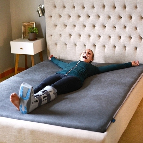 a woman laying on a bed with a knee brace.