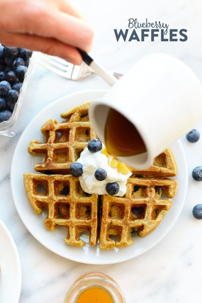 blueberry waffles being drizzled with syrup