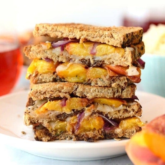 a stack of *gouda* grilled cheese sandwiches with peaches and onions.