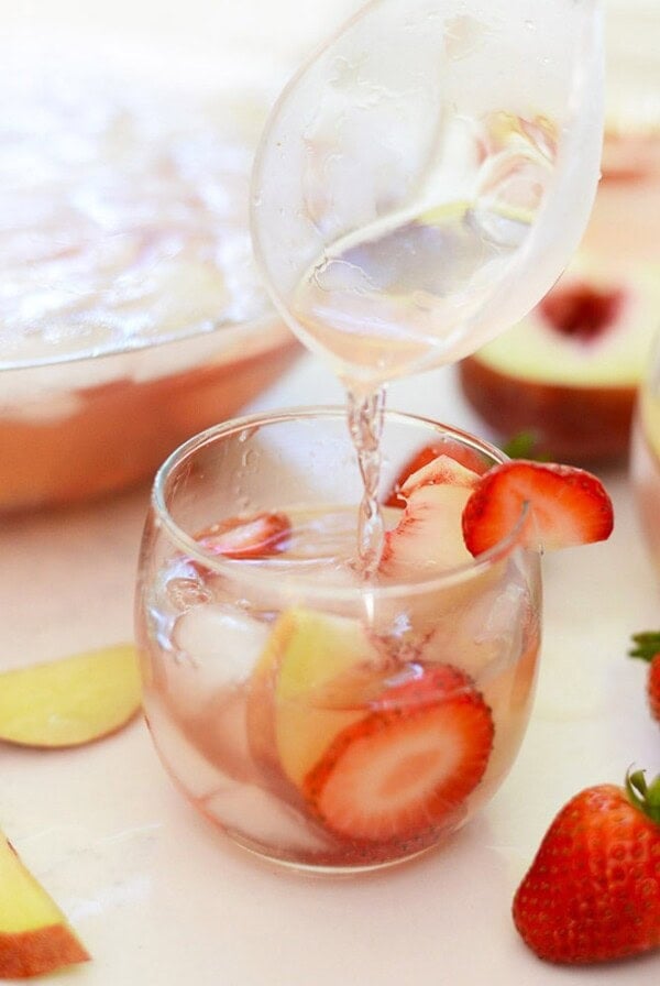 strawberry peach rose sangria being ladled into a stemless wine glass