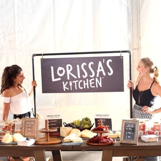 Two Fit Foodie Travels bloggers standing in front of a table with a sign that says Lorissa's Kitchen at Nantucket.