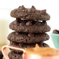 A stack of Double Chocolate Peanut Butter Cookies on a wooden cutting board.