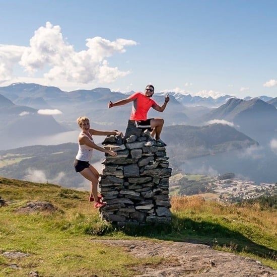 two people standing on top of a rock in the mountains.