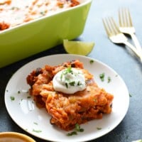 A chicken enchilada casserole topped with sour cream and limes.