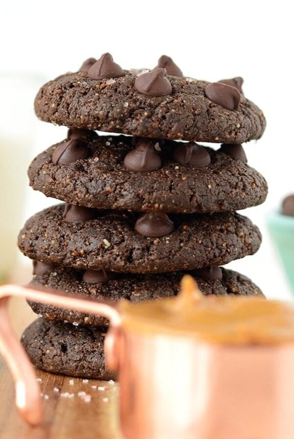 A stack of double chocolate peanut butter cookies on a wooden cutting board.