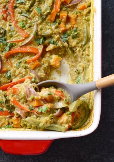 a curry quinoa casserole dish with vegetables and a spoon.