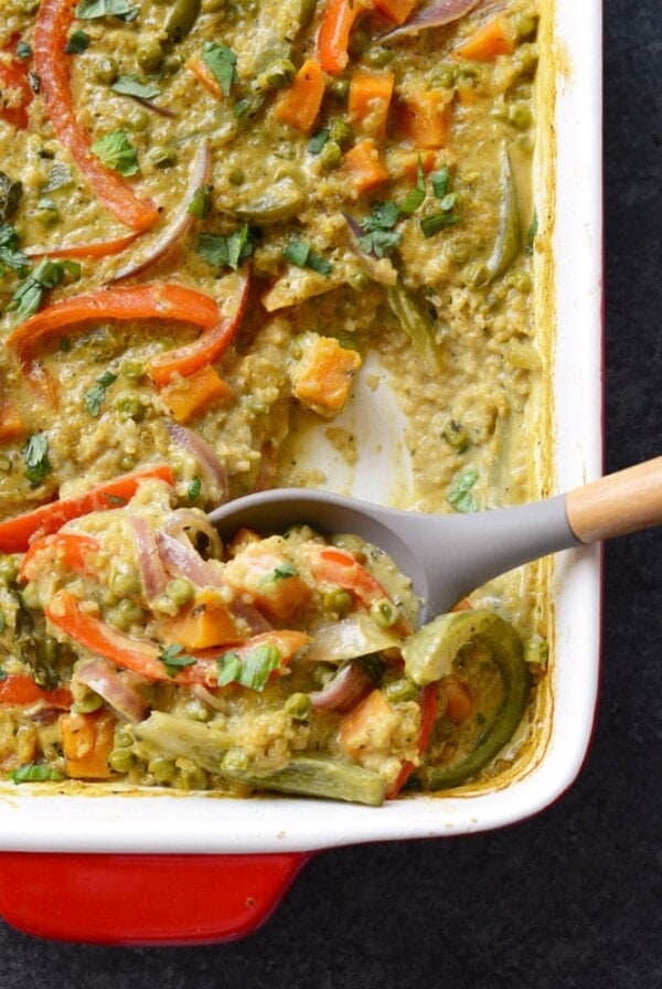 a curry quinoa casserole dish with vegetables and a spoon.
