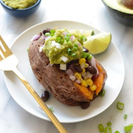 Mexican stuffed sweet potatoes with avocado and guacamole on a plate.