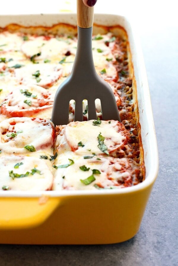 a person using a spatula to remove a Naked Lasagna from a baking dish.