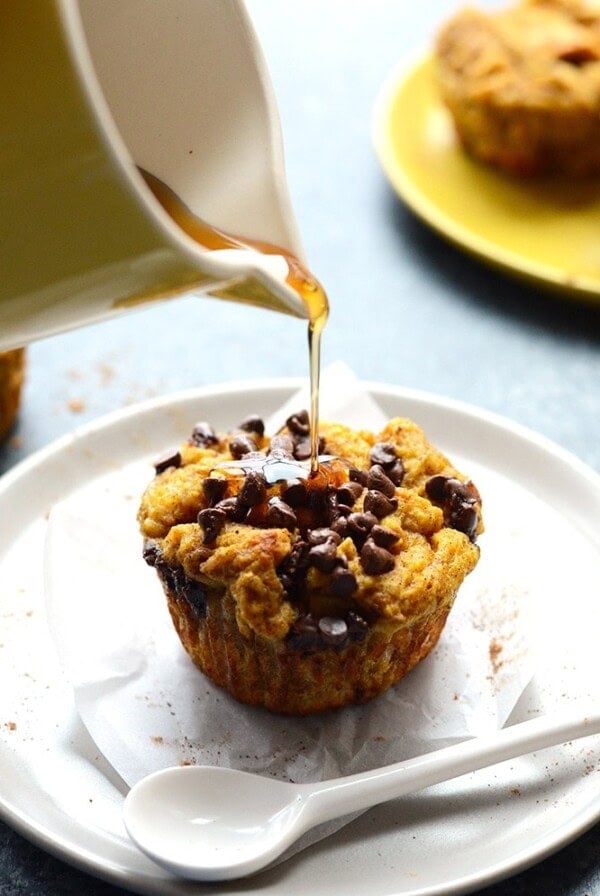 A person is pouring pumpkin liquid onto a french toast muffin cup.