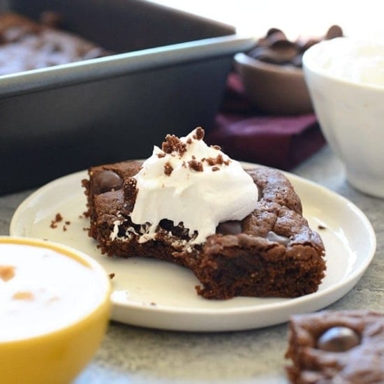 Cashew Butter Brownies topped with whipped cream on a plate.