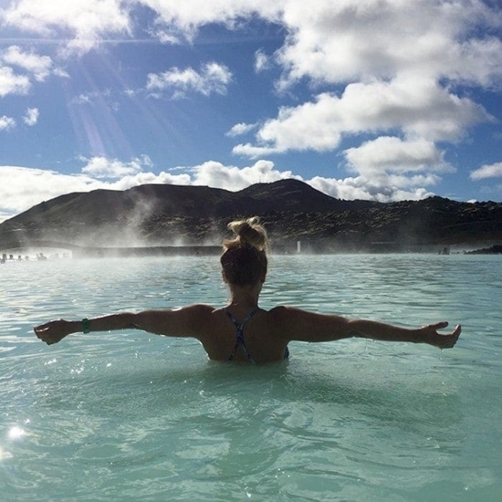 a woman in a blue lagoon with her arms outstretched.