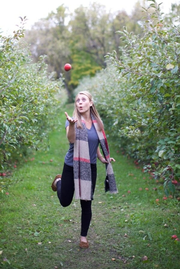 a woman running through Minnetonka Orchards with an apple in her hand.