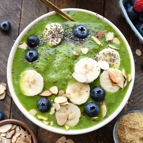 healthy green smoothie bowl topped with fruit and nuts and chia seeds