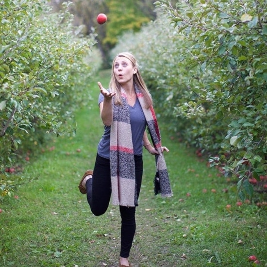 A woman catching an apple at Minnetonka Orchards.