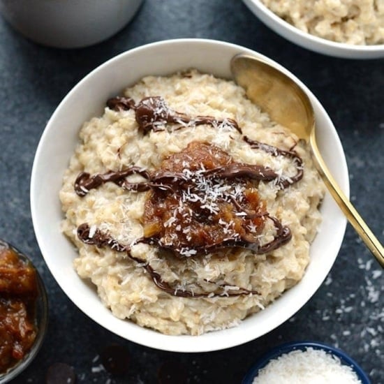 A bowl of steel cut oatmeal with a hint of samoa flavor, topped with rich chocolate sauce, served with a spoon.