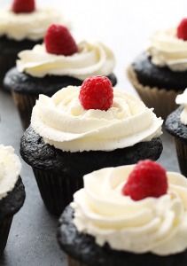 healthier chocolate cupcakes topped with vanilla frosting and a fresh raspberry