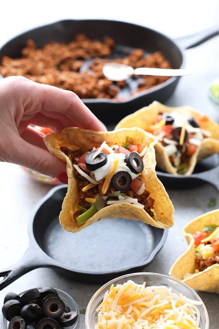 A hand holding a mini taco cup.