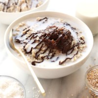 A crock pot bowl of steel cut oatmeal topped with chocolate drizzle, served with a glass of milk.
