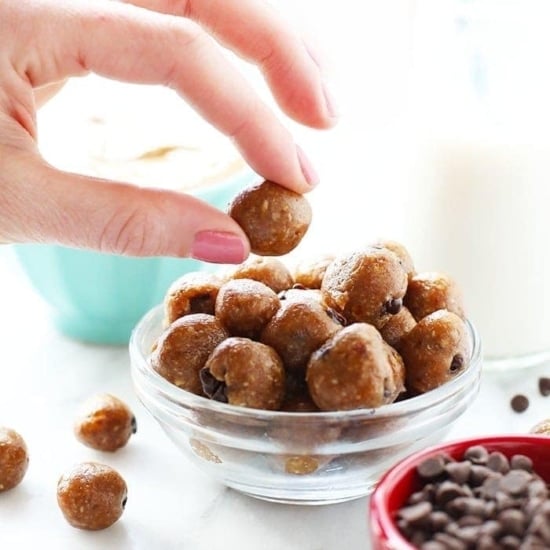 a hand reaching into a bowl of healthy cookie dough bites.
