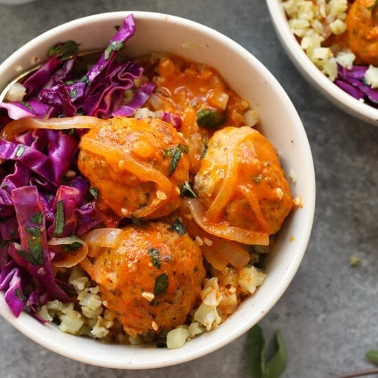 Two bowls with red curry meatballs and cabbage.