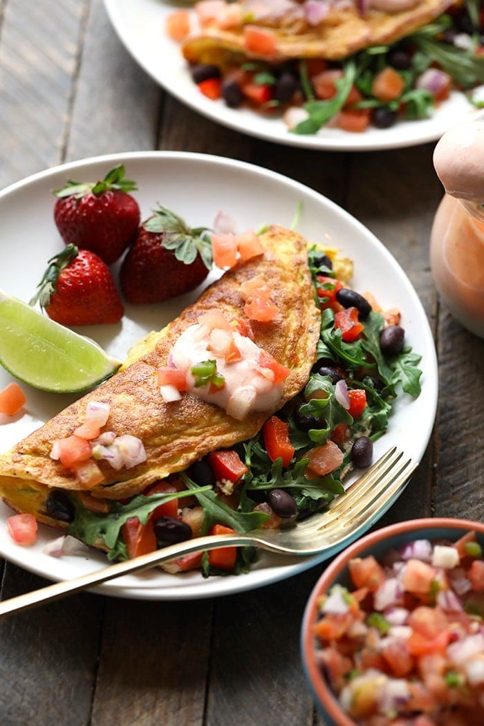 a plate of veggie omelette with black beans and strawberries.