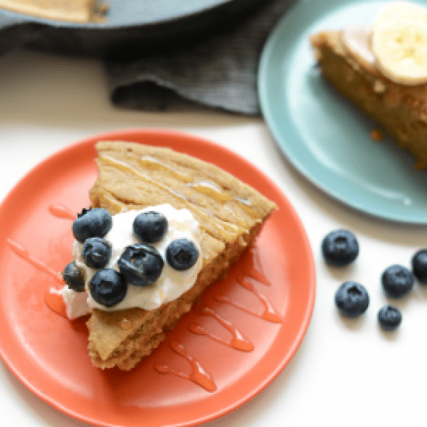 A plate of pancakes with blueberries and whipped cream.