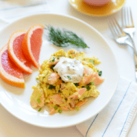 Salmon scramble on a white plate with orange slices.