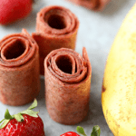 A group of banana and strawberry wraps on a table.