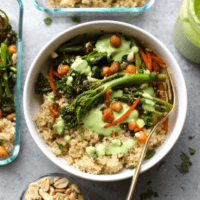 A bowl of quinoa, broccoli and greens with a green dressing.