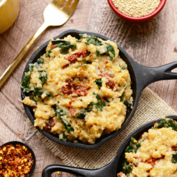 A bowl of quinoa and spinach on a wooden table.