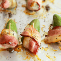 Bacon wrapped pickles on a baking sheet.