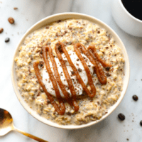 A bowl of oatmeal with caramel sauce and coffee.
