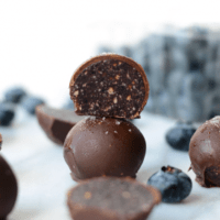 A stack of chocolate truffles with blueberries on top.