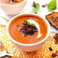 Two bowls of tomato soup with toasted bread.