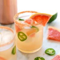 Two glasses of grapefruit margarita with jalapeos and limes.