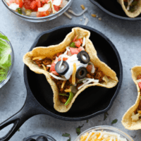 A group of tacos in a black skillet on a table.
