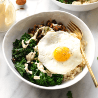 A bowl of rice and kale with an egg on top.